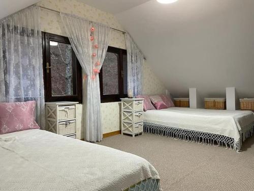 a bedroom with two beds and two windows at Casa din Pădure in Petroşani