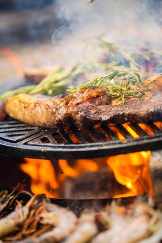 a steak and vegetables cooking on a grill with flames at Let's Meet Elewijt in Elewijt