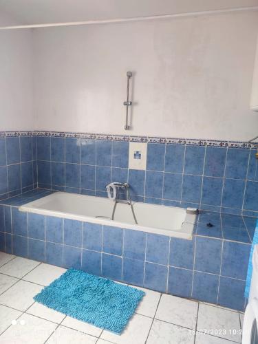 y baño con bañera y azulejos azules. en Villa Saphira en Antananarivo