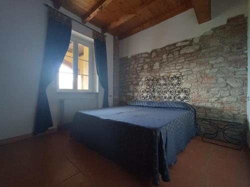 a bedroom with a blue bed in a stone wall at Villa Luisa in Ziano Piacentino