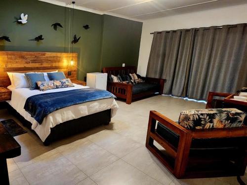 a bedroom with a bed and a chair and a couch at Villa-né Guesthouse in Potchefstroom
