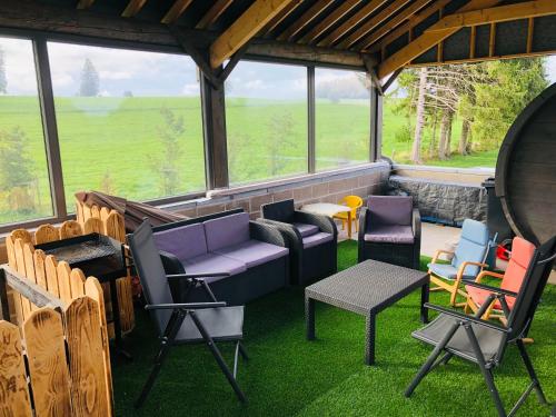 a room with chairs and furniture on the grass at PEGASUS I - 2 chambres de luxe, cuisine, salon, 2 terrasses et sauna in Vielsalm