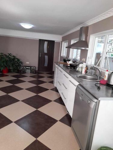 a kitchen with a checkered floor with a sink and refrigerator at Zhanas home anaklia in Anaklia