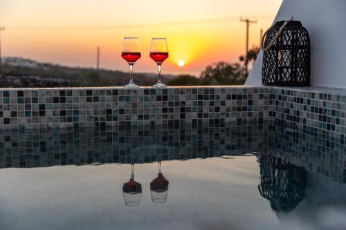 two glasses of wine sitting on the edge of a swimming pool at Theophrasti Suites in Foinikiá