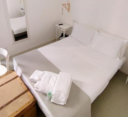 un letto bianco con cuscini e asciugamani bianchi di B&b Sedilequattro a Castellaneta