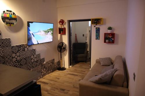 a living room with a couch and a television on the wall at Orticello Appartment in San Sperate