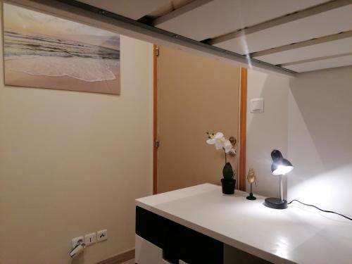 Cette chambre comprend un bureau avec une lampe et des fleurs. dans l'établissement L’étoile de Tunis, à Boulogne-sur-Mer