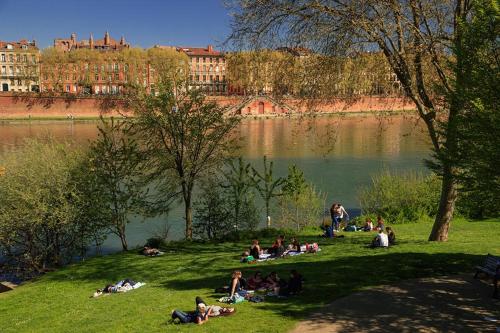Un groupe de personnes assises sur l'herbe près d'un lac dans l'établissement Superbe maison avec patio - Famille - Entreprise, à Toulouse