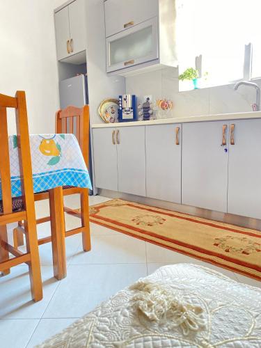 a kitchen with white cabinets and a table and a chair at Villa Meta - Welcoming You with Byrek & Traditional Meals in Gusmar