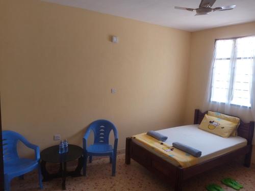 una camera da letto con sedie blu, un letto e un tavolo di Ferry Gardens a Mombasa