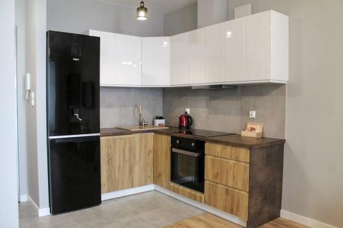 a kitchen with white cabinets and a black refrigerator at Golden Apartments Gdansk&P29 in Gdańsk