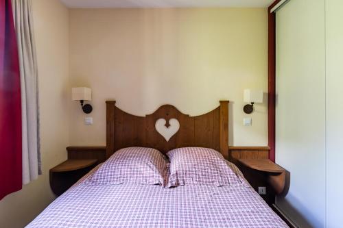 a bed with a wooden head board with a heart on it at Carpe Diem à L'Alpaga - Centre station in La Salle Les Alpes