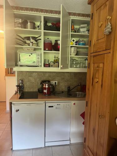 une cuisine avec des armoires blanches et un évier dans l'établissement Le Refuge de Léonor, à Valmorel