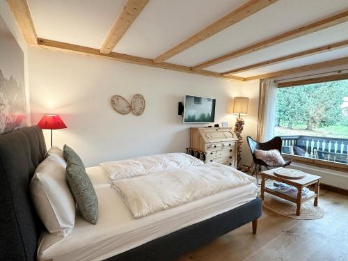 1 dormitorio con 1 cama, TV y ventana en Natur, Erholung, moderne 35m2 für 2P mit Auto PP - SP19, en Pontresina
