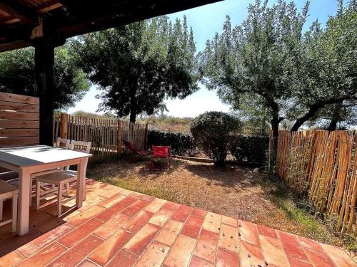 une terrasse avec une table, des arbres et une clôture dans l'établissement Studio avec jardin privatif au calme place de parking, à Hyères