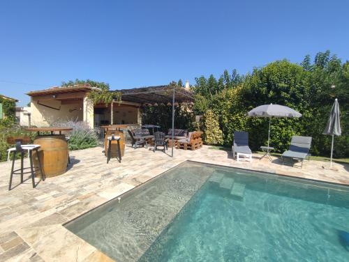un cortile con piscina, tavolo e sedie di Villa moderne dans la tranquillité de la campagne a Caderousse
