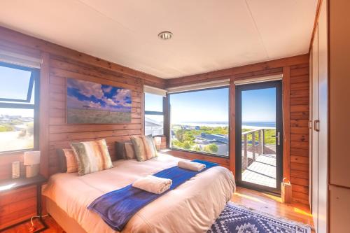Un dormitorio con una cama con una ventana grande. en Upmarket, Spacious and Stunning Sea Views, en Cape St. Francis