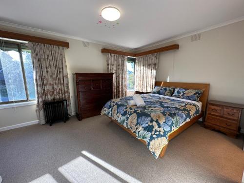 um quarto com uma cama, uma cómoda e janelas em Central Sunbury home with top hill views, high speed Wifi, Netflix & Prime Video em Sunbury