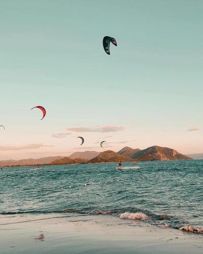 a group of people flying kites in the ocean at Apartman Olimp in Metković