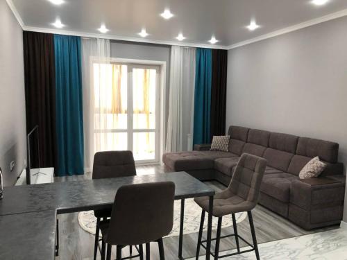 sala de estar con sofá, mesa y sillas en Новая квартира в ЖК Улытау, en Karagandá