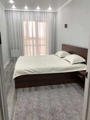 1 dormitorio con 1 cama grande y ventana grande en Новая квартира в ЖК Улытау en Karagandá