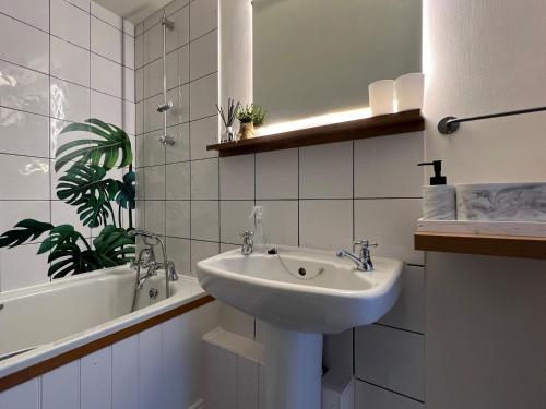 a white bathroom with a sink and a bath tub at Westgate Garden riverside in Canterbury