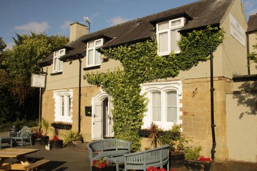 a ivycovered house with tables and chairs in front of it at White Swan Inn in Belford