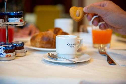 uma pessoa comendo um donut ao lado de uma xícara de café em Concordia Hotel em San Possidonio