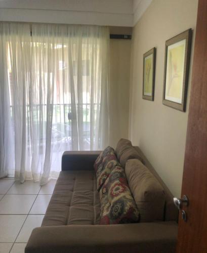 een bruine bank in een woonkamer met een raam bij aldeia das aguas hotel in Além Paraíba