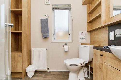 a bathroom with a toilet and a sink and a window at The Lodge in Ryde