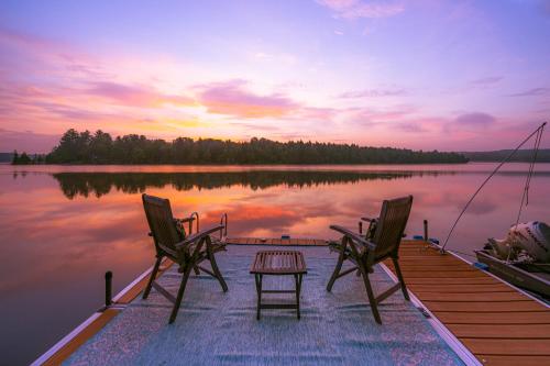 a dock with two chairs and a table on a lake at Dragonwood Retreat 