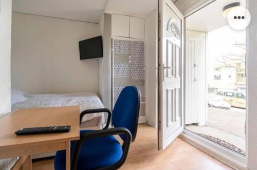 Habitación con escritorio, silla azul y cama. en 4Bed Castle in Medway free sports channel parking en Chatham