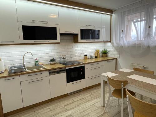 a kitchen with white cabinets and a dining table at Apartament Natalia in Hel