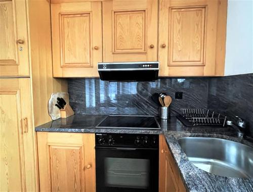 um balcão de cozinha com um lavatório e uma máquina de lavar louça em Lovely Family Apartment with Patio &Fireplace &Parking em Laax