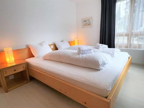 um quarto com uma cama com lençóis brancos e almofadas em Lovely Family Apartment with Patio &Fireplace &Parking em Laax