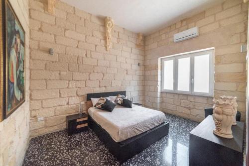 1 dormitorio con 1 cama en una pared de ladrillo en Il colore del Salento, en Carpignano Salentino