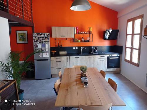 - une cuisine avec une table en bois et des murs orange dans l'établissement Loft vue Palais des Papes, à Avignon