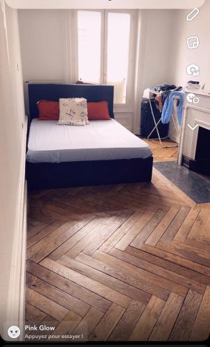 a bedroom with a bed on a wooden floor at Location chambre long et court séjour in Saint-Étienne