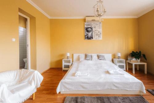 a bedroom with a white bed and a yellow wall at Páva Panzió in Soltvadkert