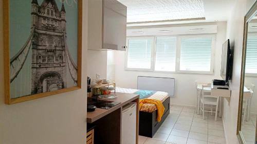 a small room with a kitchen and a room with a bed at Bron centre appartement meublé avec jacuzzi in Bron