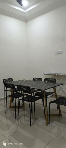 stół i krzesła w pokoju z białą ścianą w obiekcie RWA Segamat homestay w mieście Segamat