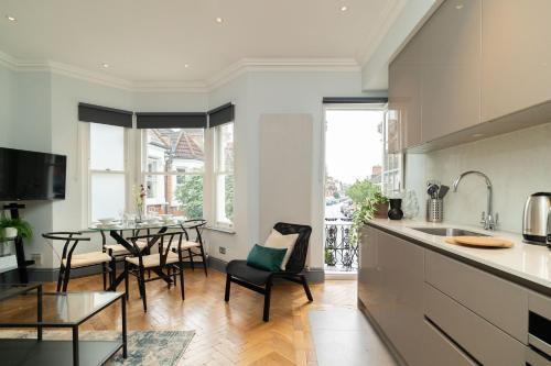 a kitchen and dining room with a table and chairs at Margravine Gardens by Viridian Apartments in London