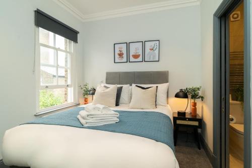 a bedroom with a bed with towels on it at Margravine Gardens by Viridian Apartments in London