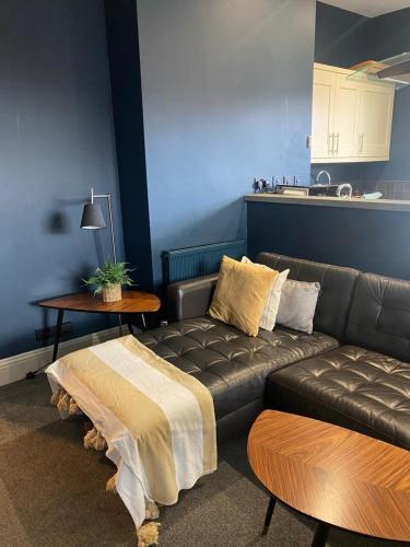 a living room with a leather couch and a table at Raby Apartment in Darlington