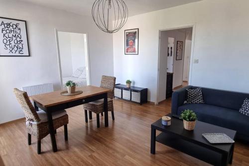 un salon avec une table et un canapé bleu dans l'établissement Super appartement, à proximité de la gare SNCF, à Avignon