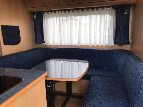 a couch in a train with a table and a window at Agri Camping italiano - Eucalyptus in Shënkoll