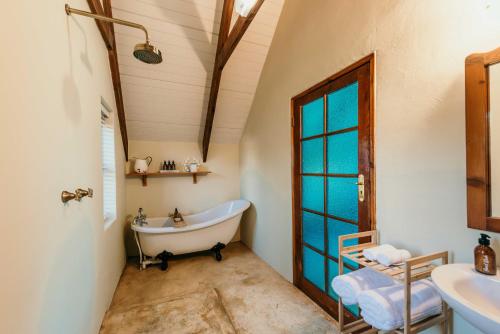 a bathroom with a tub and a sink at Silky Oaks Couples Retreat in Riebeek-Kasteel