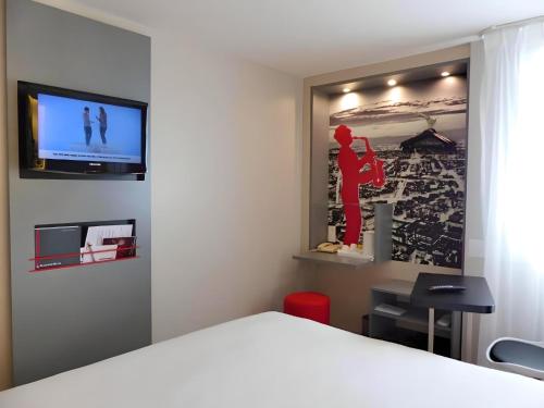 サン・トゥアンにあるKyriad Paris Saint Ouenの壁にテレビとベッドが備わる客室です。