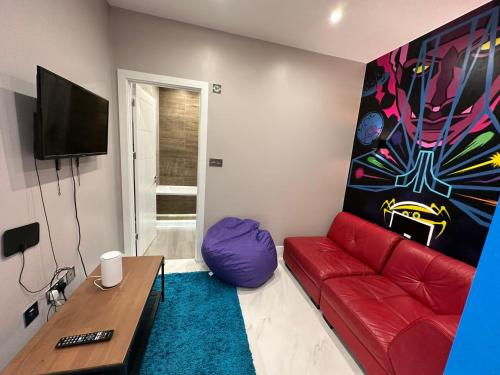 ロンドンにあるThemed Stunning 1-Bed Apartment in Londonのリビングルーム(赤いソファ、テレビ付)
