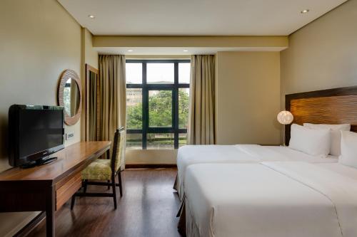 a hotel room with a bed and a desk and a television at Protea Hotel by Marriott Benin City Select Emotan in Benin City